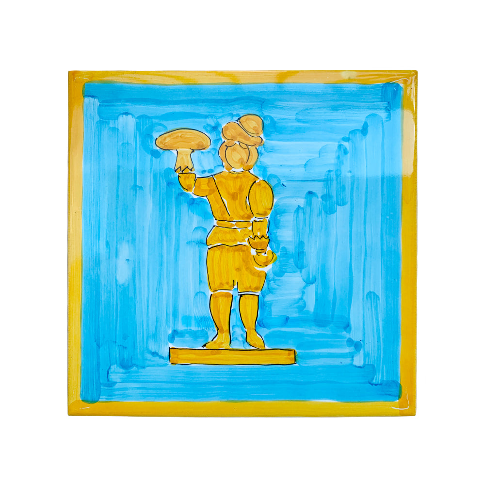 Maiolica artigianale PIL PIL in terracotta di pasta rossa smaltata, dipinta a mano con figura stilizzata ispirata alla tradizione partenopea. Raffigura un personaggio in abiti storici che regge una pizza, su fondo azzurro con cornice gialla. Toni caldi e ironici, ideale come pezzo unico per ambienti conviviali e creativi.
