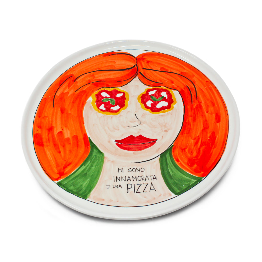 Piatto pizza artigianale in ceramica dipinto a mano con volto femminile dai capelli rossi e occhi a forma di pizza Margherita Sul piatto e presente la scritta Mi sono innamorata di una Pizza Decorazione originale in stile pop art ideale per arredare cucina pizzeria o come regalo per gli amanti della pizza