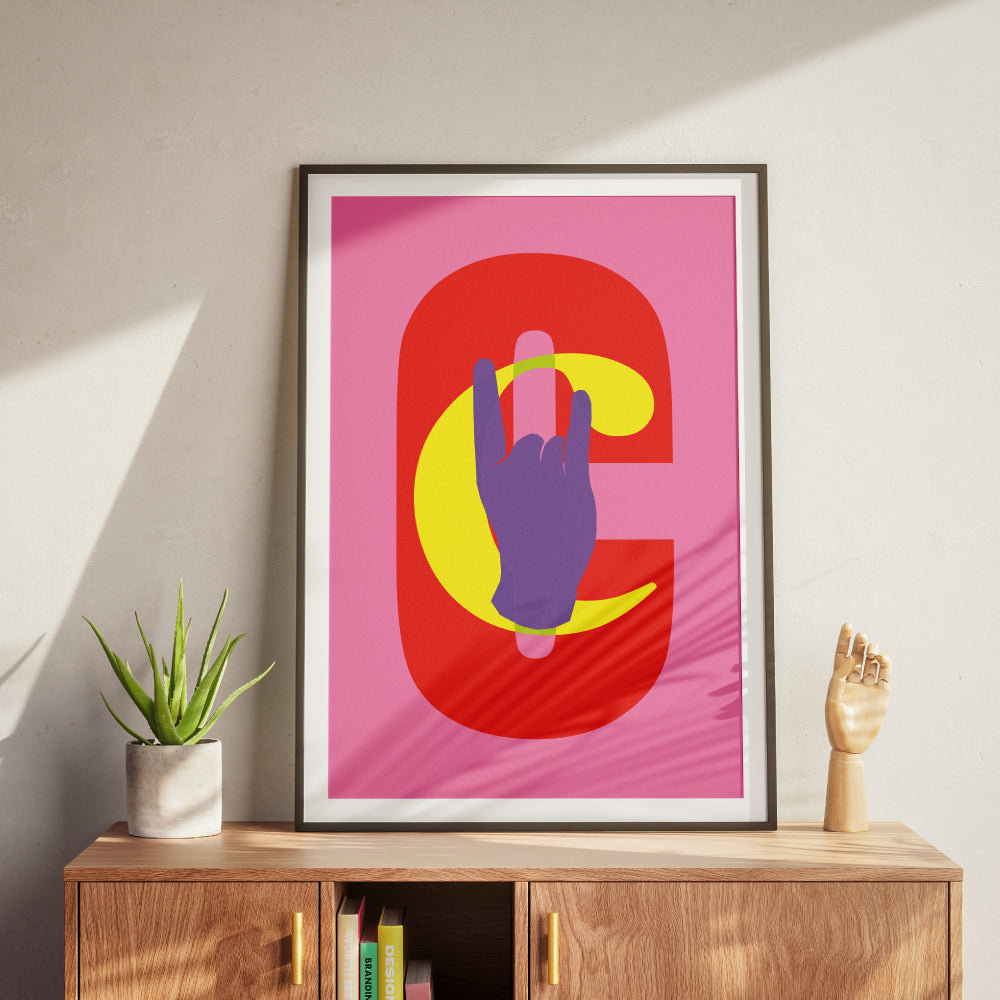 Poster grafico moderno con sfondo rosa, lettera C rossa e mano viola stilizzata che fa il gesto delle corna, ideale per arredare spazi creativi, interni pop, studi di design e ambienti contemporanei.