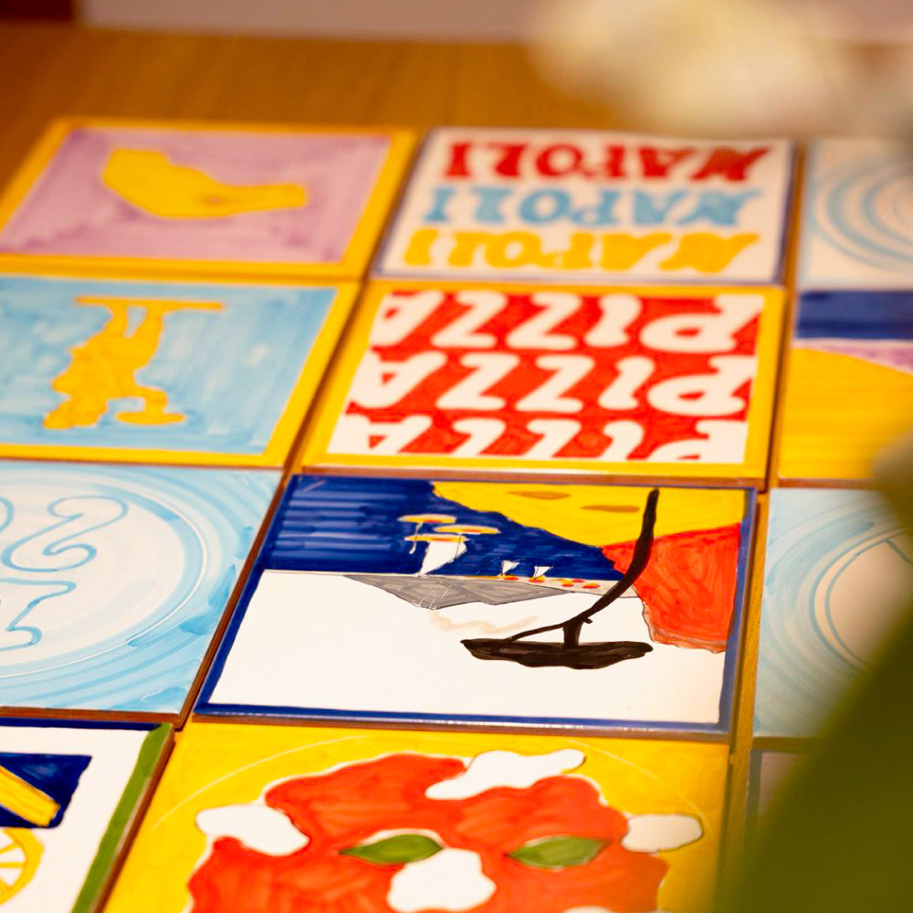 Maiolica artigianale dipinta a mano con paesaggio del Golfo di Napoli, Vesuvio fumante, mare blu intenso, barche colorate e scogliera rossa su terracotta di pasta rossa smaltata.