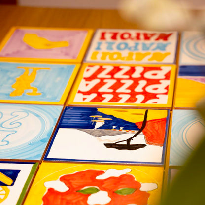 Maiolica artigianale dipinta a mano con paesaggio del Golfo di Napoli, Vesuvio fumante, mare blu intenso, barche colorate e scogliera rossa su terracotta di pasta rossa smaltata.