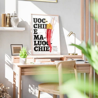 Il poster raffigura un grande corno portafortuna napoletano di colore rosso, sormontato da una corona dorata, disegnato con tratti grafici stilizzati. Sullo sfondo, in caratteri neri e grandi, appare la scritta dialettale Uocchie e Maluocchie. In basso a destra e presente un testo esplicativo che richiama un proverbio napoletano legato alla tradizione degli amuleti contro il malocchio