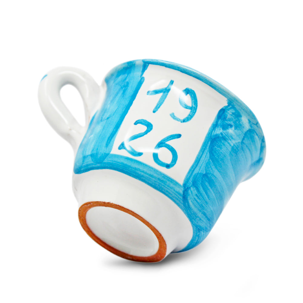 Può includere: Una tazza da tè in ceramica blu e bianca con i numeri "1926" dipinti sopra. I numeri sono visualizzati anche in un carattere più grande sopra la tazza. La tazza ha un manico bianco e un design dipinto.
