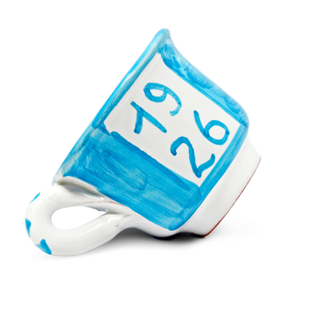 Può includere: Una tazza da tè in ceramica blu e bianca con i numeri "1926" dipinti sopra. I numeri sono visualizzati anche in un carattere più grande sopra la tazza. La tazza ha un manico bianco e un design dipinto.
