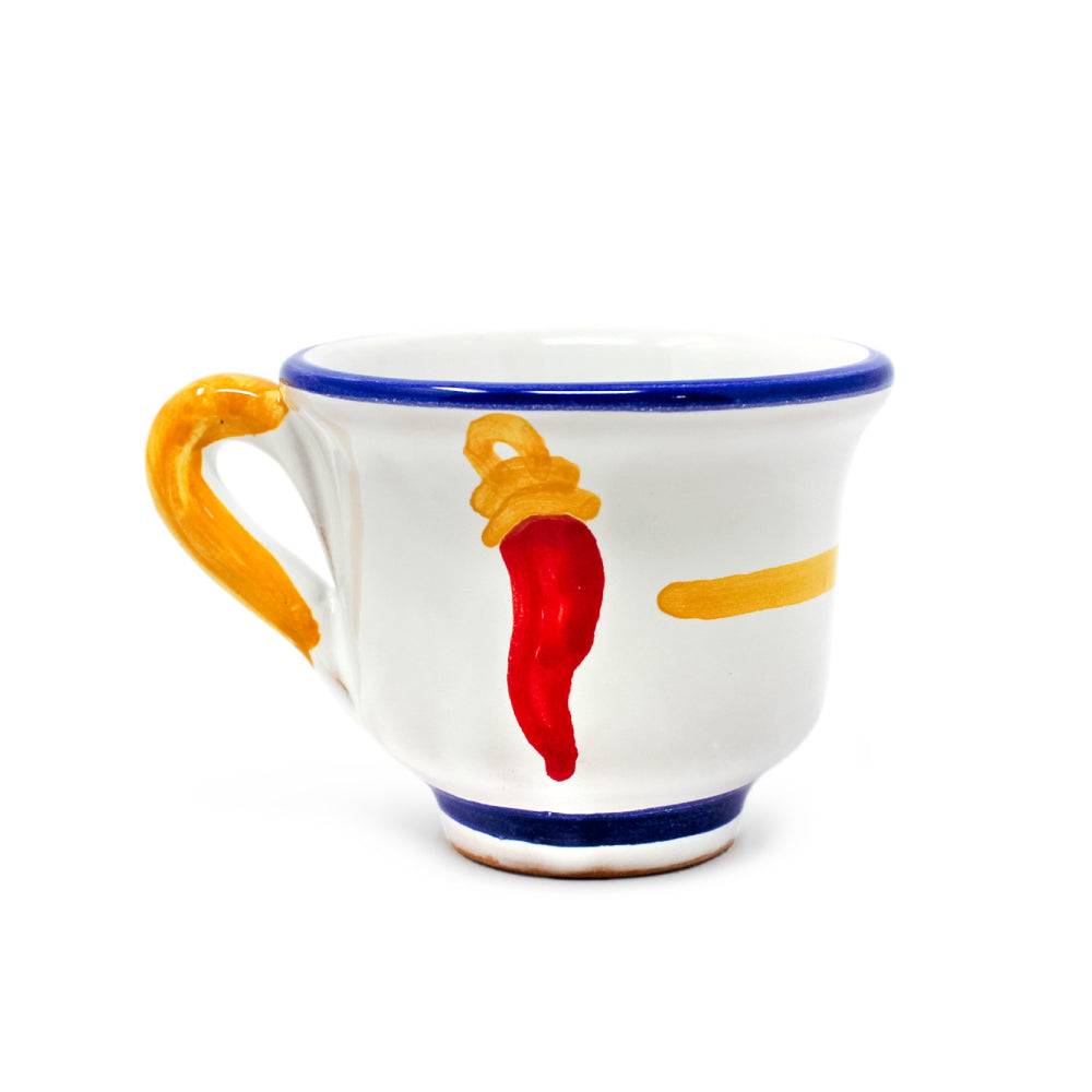 Tazzina da caffè artigianale Pil Pil Design Partenopeo, realizzata in terracotta di pasta rossa smaltata e dipinta a mano. Ceramica bianca con bordo blu, manico giallo e decorazione centrale raffigurante il tradizionale cornicello rosso napoletano, simbolo di fortuna e protezione contro il malocchio. Un oggetto di artigianato Made in Italy, ispirato alla cultura e alla scaramanzia partenopea, ideale come idea regalo originale per gli amanti di Napoli e del caffè.